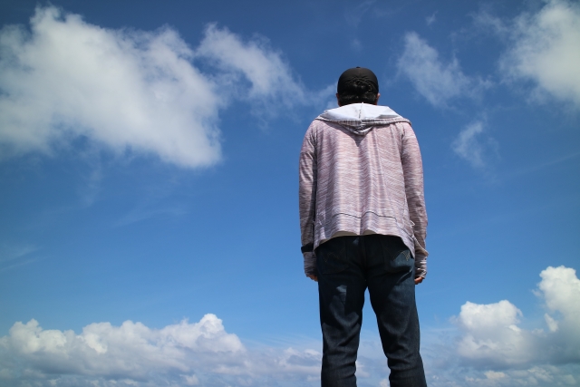 営業に行くか迷いながら、将来について考えて立ち止まっている男性の後ろ姿