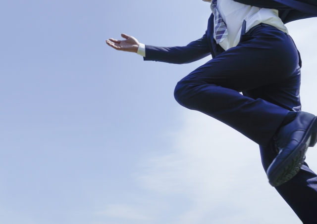 スーツ姿で前に踏み出すビジネスパーソンの動きを表した写真