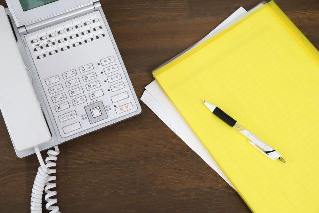 電話機とメモ帳とペンの写真（テレアポ営業の業務イメージ）
