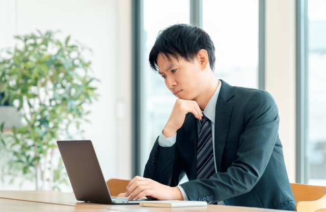 営業は数字だけの仕事なのか不安を感じながらパソコンを見る若手ビジネスマンのイメージ