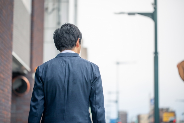 スーツ姿で街を歩く営業担当者の後ろ姿