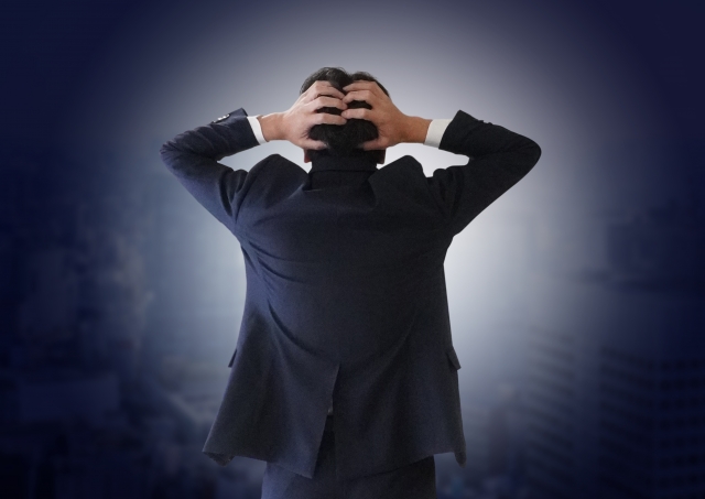 営業で人生詰んだと感じて頭を抱えるスーツ姿の男性の後ろ姿