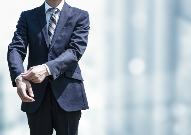 営業マンが商談や訪問前にスーツの袖を整えて準備しているイメージ