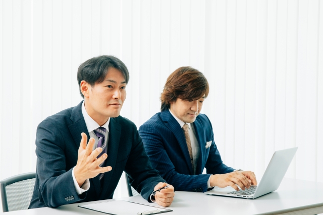 スーツ姿の男性2人が面談や打ち合わせをしている様子を写したイメージ画像
