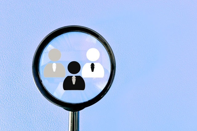 虫眼鏡越しに人物アイコンが見える、求人選びや人材探しをイメージした画像