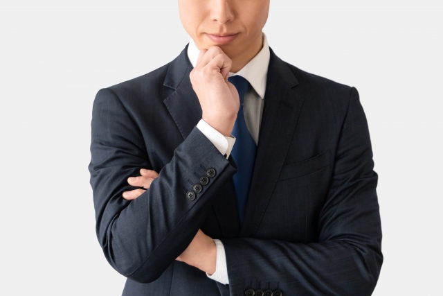 スーツ姿の男性が腕を組んで考えているイメージ画像
