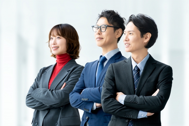 スーツ姿の男女3人が前を向いて立つ、営業転職や就職後の前向きなイメージ画像