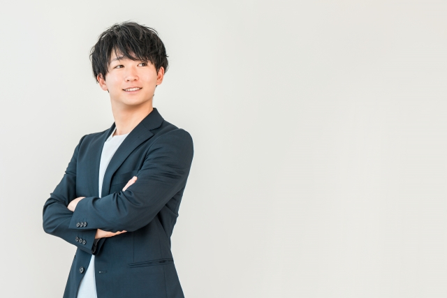 スーツ姿で腕組みをして立つ若い男性のイメージ