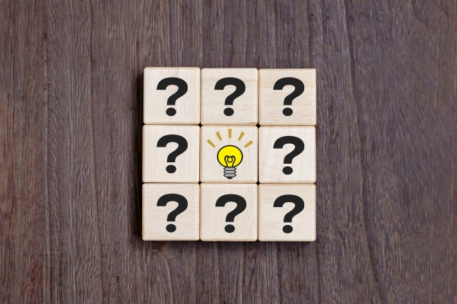 疑問符の木製ブロックと電球の画像。営業転職で迷う人が判断材料を探すイメージ。