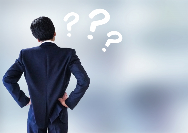 今の仕事を続けるか営業に転職するか迷い、疑問を抱えて立ち止まるビジネスマン