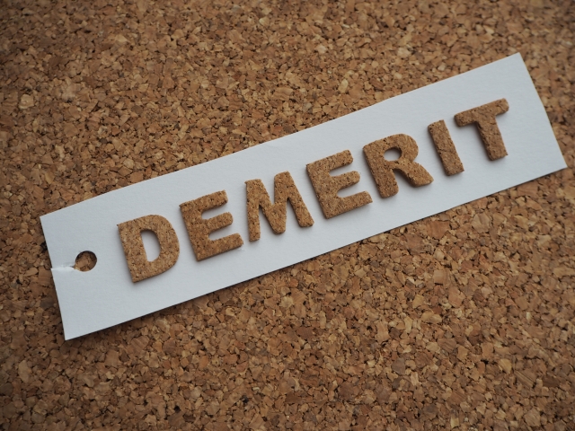 コルクボードの上に「DEMERIT」と書かれたタグが置かれているデメリットのイメージ画像