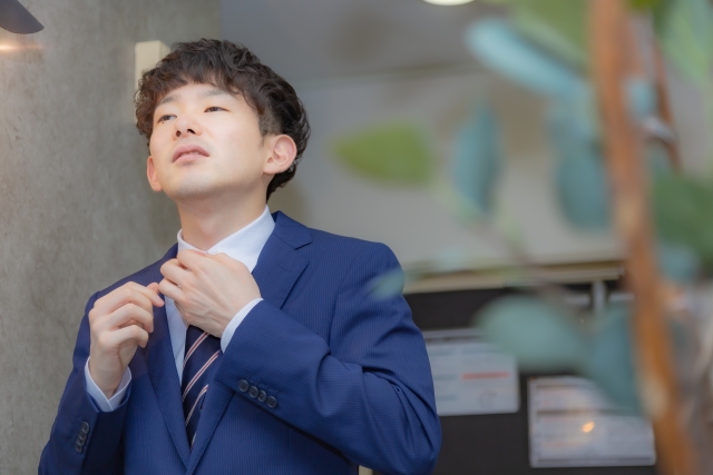 営業職の仕事前に身だしなみを整える若い男性