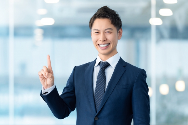 人差し指を立てて笑顔でポイントを説明する営業担当者