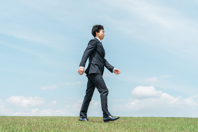 営業職のキャリアパスを考えながら前へ進むスーツ姿の男性
