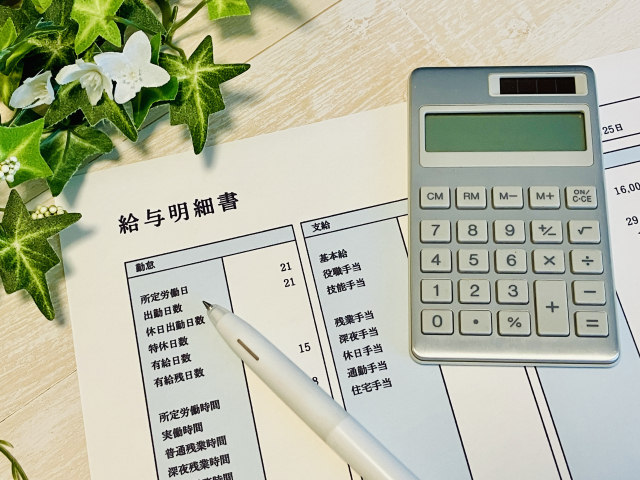 給与明細と電卓を使って営業職の年収や給与条件を確認するイメージ