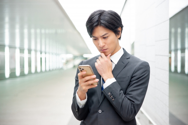 スマートフォンで営業職の求人情報を確認する男性
