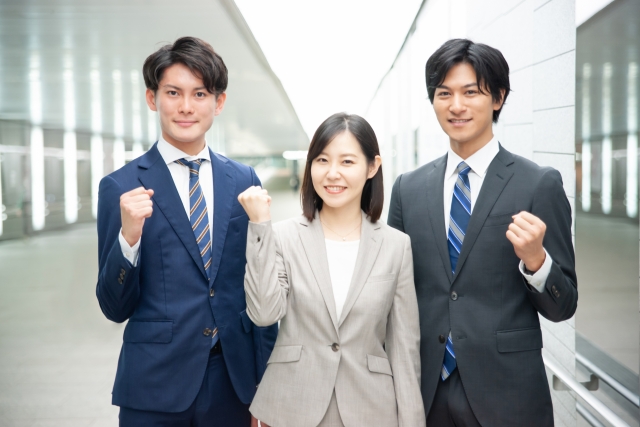 前向きな表情でガッツポーズをする3人のビジネスパーソンの画像